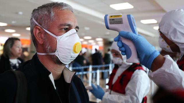 Viajeros utilizan mascarillas en el Aeropuerto internacional Mariscal Sucre de Quito. El Ministerio de Salud Publica de Ecuador refuerza junto a su personal los controles sanitarios mediante la toma de temperatura, colocando alcohol en las manos, y brindando información sobre el coronavirus. (EFE).