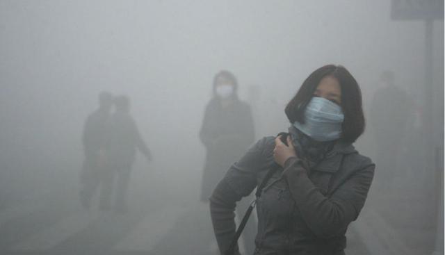 Una mujer camina en medio del smog de Pequín, donde la polución de cada partícula del aire supera cuarenta veces los estándares internacionales. (Foto: Kyodo News)