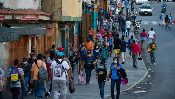 Personas con mascarillas caminan por una calle del barrio de Petare en Caracas, el 21 de diciembre de 2020, en medio de la pandemia del COVID-19. Venzuela es el país latinoamericano peor situado como "el país más feliz del mundo". (Foto: Cristian Hernandez / AFP)