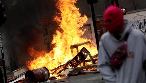 Un manifestante encapuchado pasa junto a una barricada en llamas durante una protesta en Chile. (REUTERS / Juan Gonzalez).