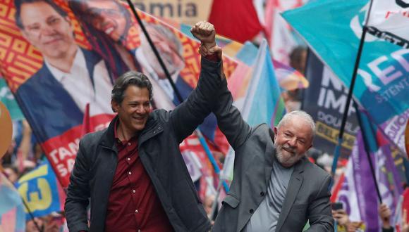 Luiz Inácio Lula da Silva (derecha), y el candidato a gobernador de Sao Paulo, Fernando Haddad, saludan a sus seguidores durante un mitin de campaña en Sao Paulo, el 1 de octubre de 2022. (MIGUEL SCHINCARIOL / AFP)