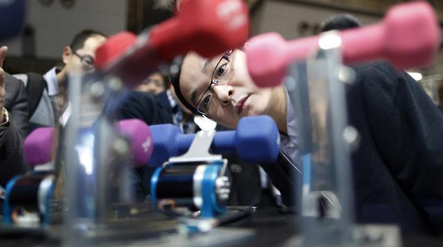 Un asistente mira dispositivos controladores para robots industriales en el stand de THK Co. en la Exposición Internacional Robot 2015 en Tokio.