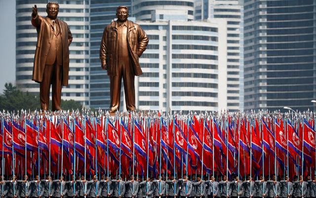 La gente lleva banderas frente a las estatuas del fundador de Corea del Norte Kim Il Sung (L) y el líder Kim Jong Il durante un desfile militar que conmemora el 105 aniversario del nacimiento Kim Il Sung. Uniformes universitarios coreanos (foto: Reuters).