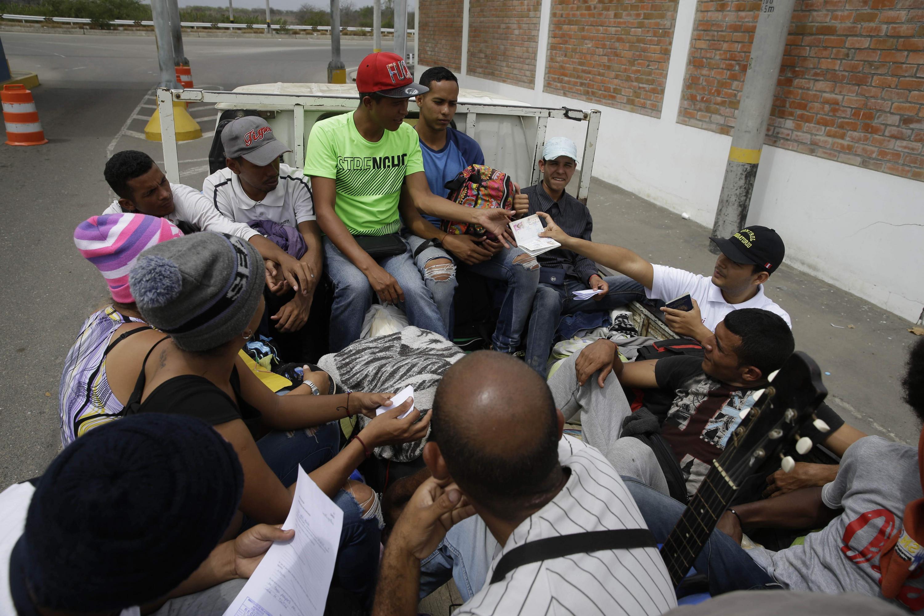 Un oficial de inmigración revisa los pasaportes de los inmigrantes venezolanos cerca de Tumbes, Perú, el 26 de agosto del 2018, mientras se sientan en la parte trasera del camión de un conductor que los recogió después de cruzar la frontera de Ecuador. (Foto: AP)