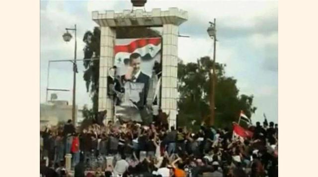 En esta imagen amateur del 25 de Marzo de 2011, una multitud de Sirios desfiguran un cartel del presidente Bashar Al-Assad.(foto:Diario ABC, S.L.)