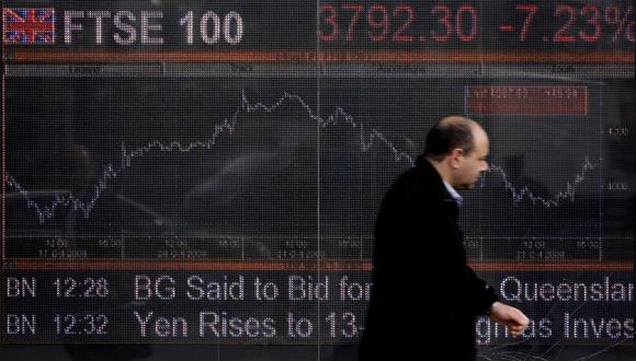 Un hombre pasa junto a una pantalla electrónica que muestra el índice de acciones FTSE 100 en Londres el 24 de octubre de 2008. (Foto de SHAUN CURRY / AFP)