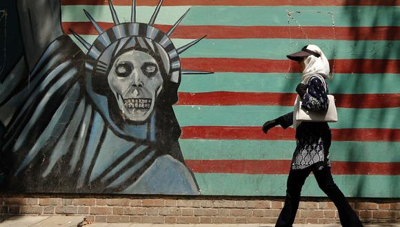 Una mujer iraní camina al lado de un mural pintado en la pared de la antigua embajada de Estados Unidos en Teherán. (Foto: AFP).