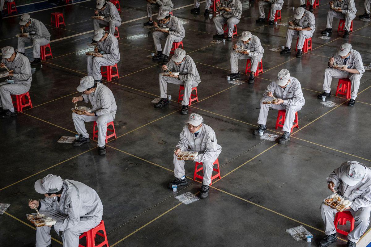 This photo taken on March 23, 2020 shows employees eating during lunch break at an auto plant of Dongfeng Honda in Wuhan in China's central Hubei province. - People in central China, where the COVID-19 coronavirus was first detected, are now allowed to go back to work and public transport has restarted, as some normality slowly returns after a two-month lockdown. (Photo by STR / AFP) / China OUT