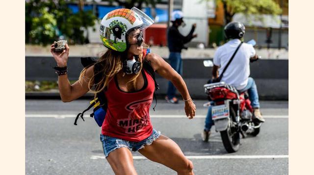 Una opositora se enfrenta con piedras a la policía antidisturbios durante la marcha contra el presidente Nicolás Maduro el 1 de mayo de 2017, en Caracas.(foto: msn).