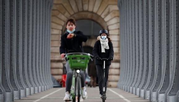 Una mujer, con mascarilla protectora, monta una scooter en el puente Pont de Bir-Hakeim en París en medio del brote de coronavirus (COVID-19) en Francia, el 18 de febrero de 2021. (REUTERS/Gonzalo Fuentes).