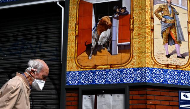 Un anciano, que usa una mascarilla como protección, pasa frente a un restaurante cerrado en Madrid, España. (Gabriel BOUYS / AFP).