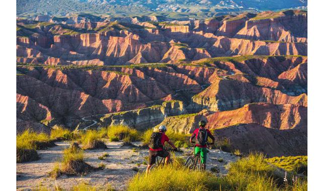 FOTO 7 | En bici por el desierto de Gorafe. A los barrancos de arenisca roja que contemplan los ciclistas de la foto se les conoce como Los Colorados, y aunque parecen el escenario de algún 'western' ambientado en las 'badlands' de Wyo