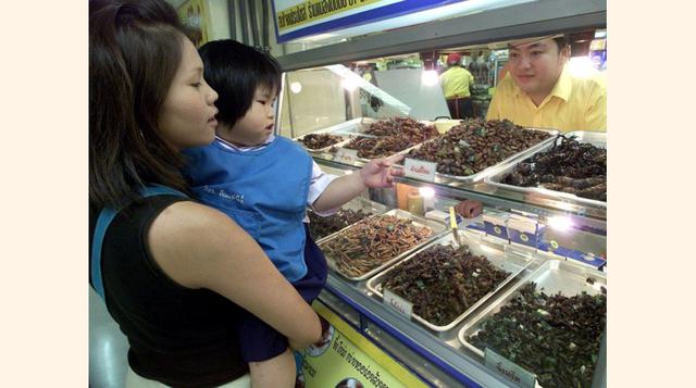 En la imagen, madre e hija pararon para comprar grillos, gusanos y saltamontes fritos en un mercado de Bangkok. (Foto: Getty)