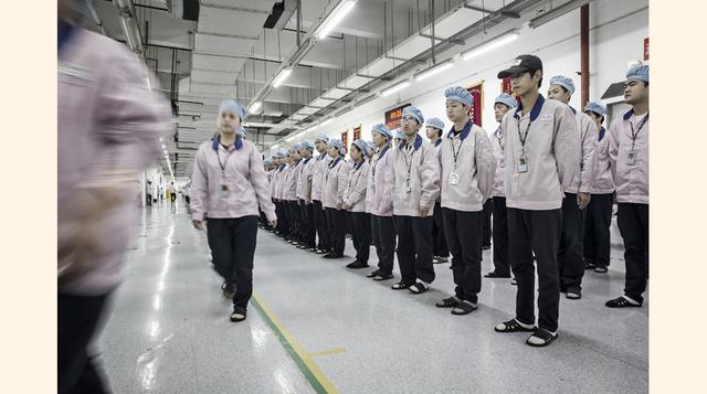 Ante una fila de armarios, se cubren el cabello con redecillas azules y cambian sus zapatos por ojotas limpias de plástico. A las 9:20, las unidades de producción de 320 trabajadores cada una se distribuyen con precisión militar en cuatro filas a la esper