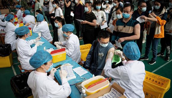 Esta foto de archivo tomada el pasdo 28 de abril de 2021 muestra a estudiantes universitarios haciendo cola para recibir la vacuna contra el coronavirus  en el Grupo Nacional Biotec de China (CNBG), en una universidad de Wuhan. (STR / AFP)