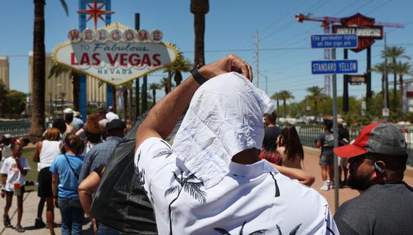 Satya Soviet Patnaik se protege del sol mientras espera en la fila para tomar una foto en el histórico cartel de Bienvenido a Las Vegas durante una ola de calor en Las Vegas, Nevada, el 14 de julio de 2023. (Foto de Ronda Churchill / AFP)