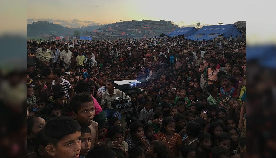 FOTO 1 | 'Desplazados'. Gran Premio en la categoría Fotógrafo del año. Niños rohingya miran una película de concientización sobre salud e higiene cerca de un campo de refugiados en Ukhia (Bangladés). Hecha con un iPhone 7. (Foto: Jashim Salam)
