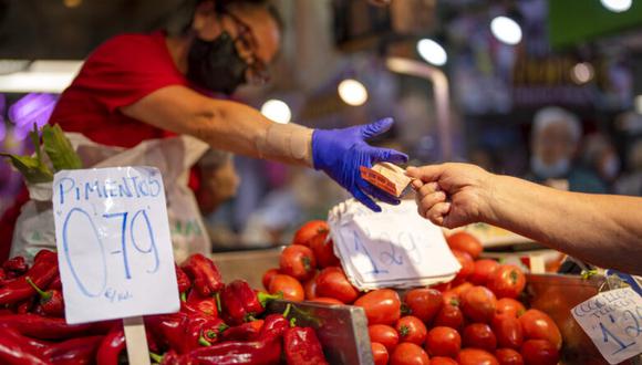 ARCHIVO - Un cliente paga verduras en el mercado Maravillas de Madrid, el jueves 12 de mayo de 2022.. (AP Foto/Manu Fernandez, Archivo)