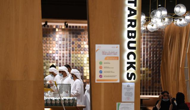 Los ciudadanos de Emiratos, que usan máscaras para protegerse contra el coronavirus, compran café en una tienda en el centro comercial de Dubai. (Karim SAHIB / AFP).