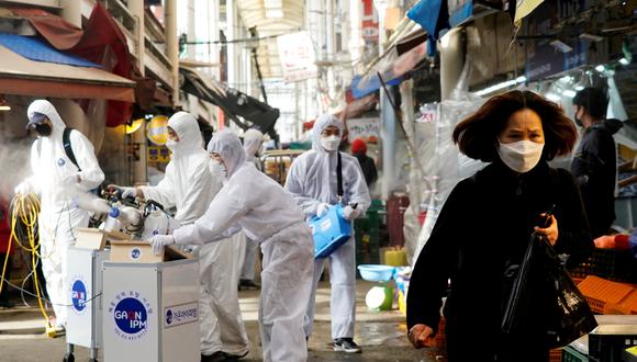 Una mujer cubierta por una mascarilla sale de un mercado que será fumigado por una compañía que ofrece servicios de desinfección en Seul, capital de Corea del Sur. El rociado de  desinfectante es parte de las medidas preventivas contra la propagación del coronavirus. (Foto: Reuters)