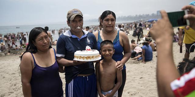 FOTO 15 | En esta imagen, tomada el 23 de febrero de 2020, un hombre posa con su pastel de cumpleaños para una fotografía con su familia, en la playa de Agua Dulce, en Lima, Perú. El medio kilómetro (milla) se arena marrón grisácea ubicado a 20 kilómetros (12 millas) al sur del centro de la capital, Lima, es un refugio para la clase trabajadora, un lugar al que los visitantes llegados de las tierras altas andinas meten por primera vez sus pies en el agua. (AP Foto/Rodrigo Abd)