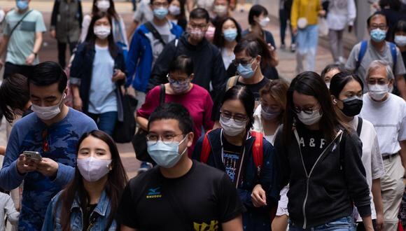 In this picture taken on October 30, 2021, people wearing face masks as a preventive measure against the Covid-19 coronavirus walk on a street in Hong Kong. - Hong Kong's decision to descend deeper into international coronavirus isolation as rivals reopen is causing consternation among managers at multinationals who see no end to a zero-Covid strategy imposed by a leadership beholden to Beijing. (Photo by Bertha WANG / AFP) / To go with AFP story Virus-health-Hong Kong-China-politics-economy, FOCUS by Jerome TAYLOR
