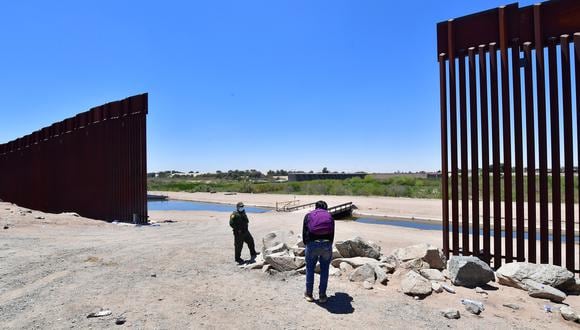 A US Border Patrol officer speaks with a migrant after he crossed into the US from Mexico through a gap in the border wall separating Algodones, Mexico, from Yuma, Arizona, on May 16, 2022. - A US Federal judge is expected to make a ruling on health policy Title 42 which has been used at the border to expel illegal immigrants due to the Covid-19 pandemic. (Photo by Frederic J. BROWN / AFP)