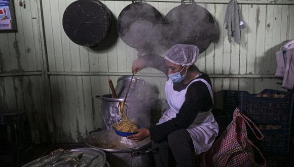 Una voluntaria cocina en un comedor social en el distrito de Villa María del Triunfo, en la periferia sur de Lima, el 21 de septiembre de 2023. (Foto de ERNESTO BENAVIDES/AFP)