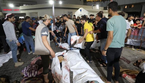 Personas reunidas alrededor de los cuerpos de palestinos fallecidos en un ataque aéreo a el hospital árabe Ahli en el centro de Gaza. (Foto de Dawood NEMER / AFP).