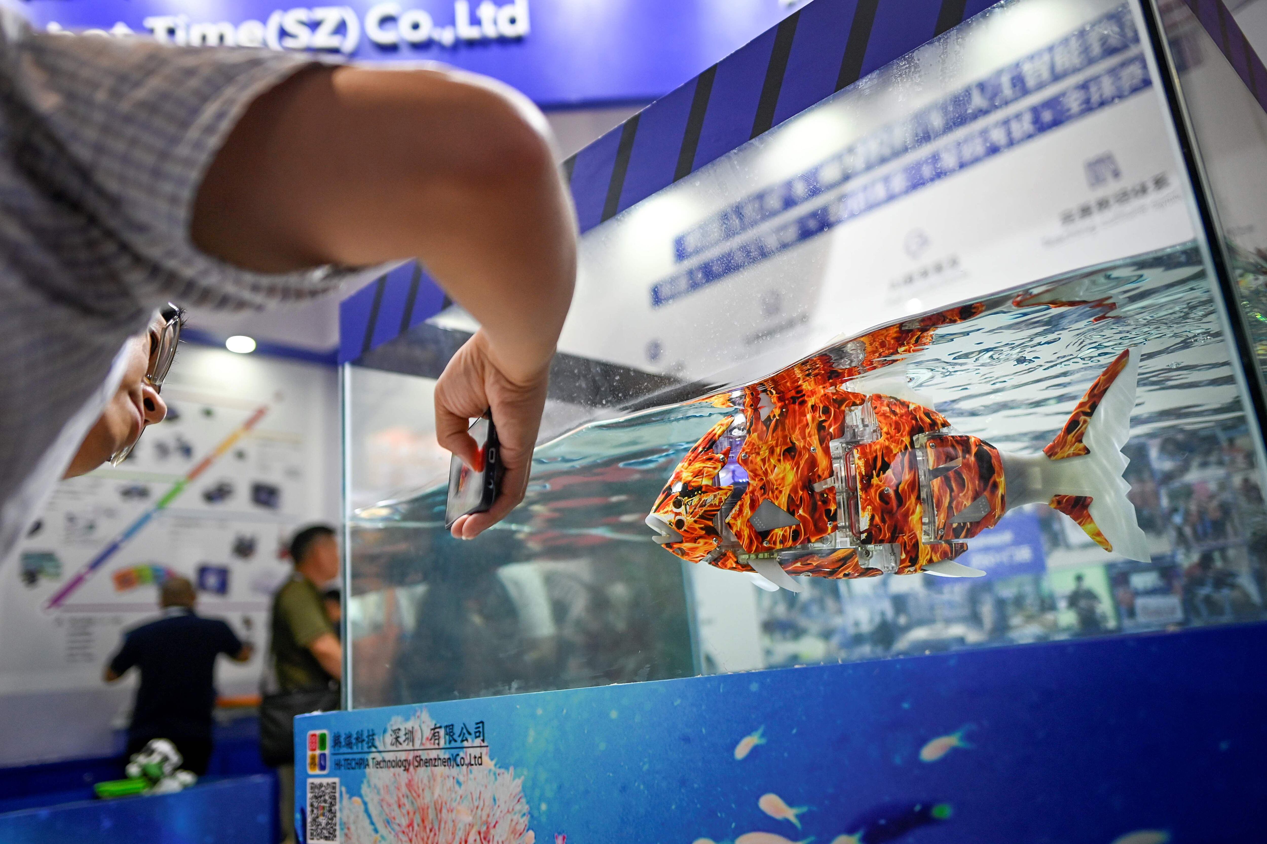 Un visitador usa su celular para tomarle una fotografía a un robot pescado en el 2019 World Robot Conference en Beijing. (Foto: AFP).