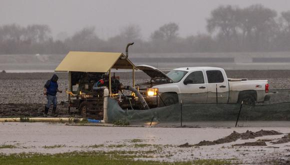 Un agricultor atiende una bomba en un campo inundado junto al río Salinas cerca de Chualar, California, el 14 de enero de 2023, mientras una serie de tormentas fluviales atmosféricas continúan causando una destrucción generalizada en todo el estado. (Foto de DAVID MCNEW / AFP)