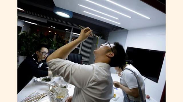 Yu Xiaojian, un empleado del Grupo Goopal, come con sus colegas durante un descanso en el trabajo cerca de la medianoche en Pekín, China. (Foto: Reuters)