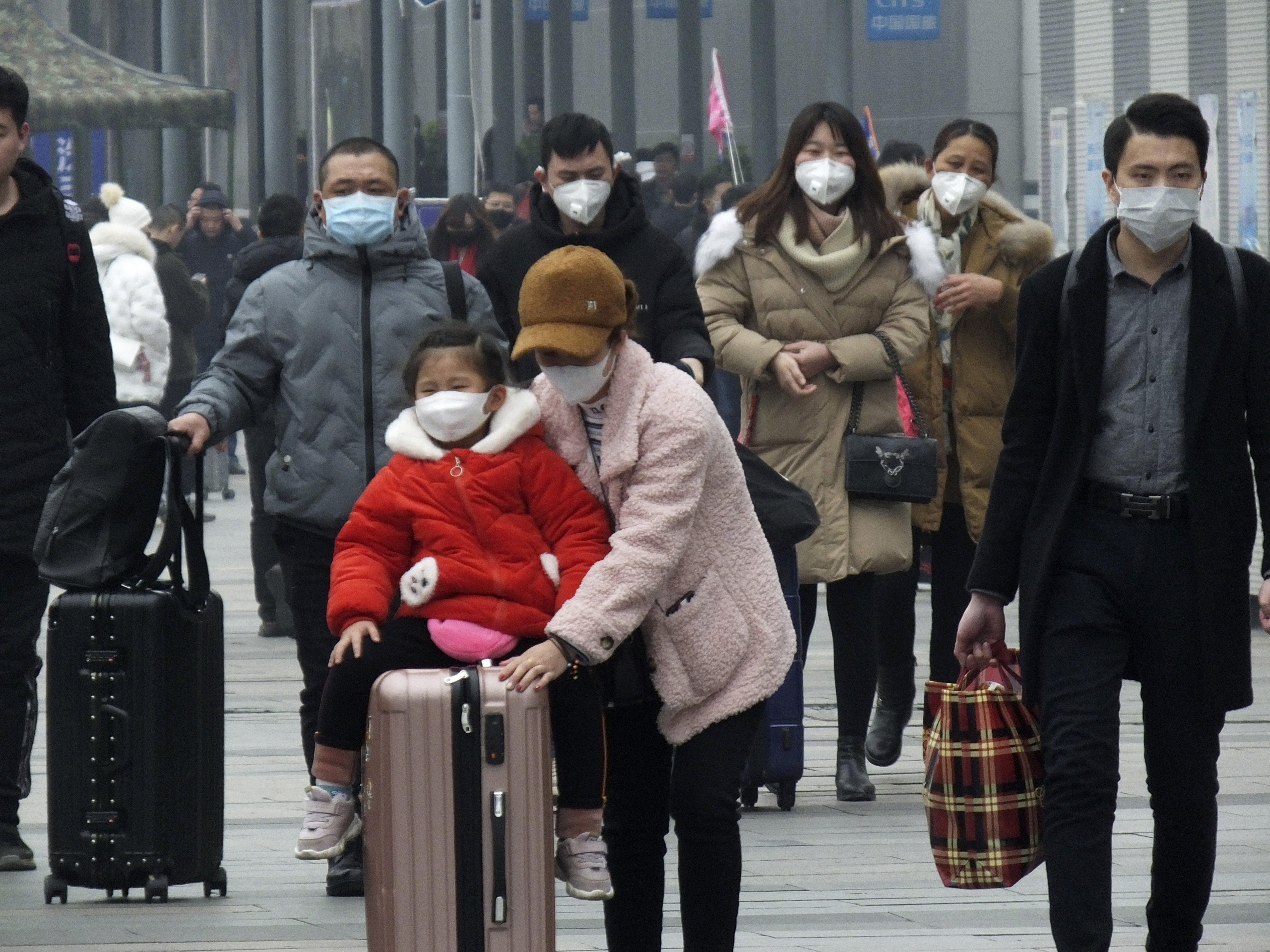 Travelers wear face masks as they walk outside a train station in Yichang in southern China's Hubei province, Tuesday, Jan. 21, 2020. Face masks sold out and temperature checks at airports and train stations became the new norm as China strove Tuesday to control the outbreak of a new virus that has reached four other countries and territories and threatens to spread further during the Lunar New Year travel rush. (Chinatopix via AP)