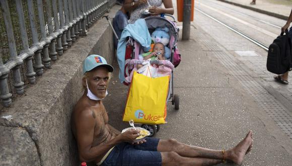 Un hombre mira a la cámara mientras come el almuerzo donado por la Fundación Leao XIII durante la pandemia de coronavirus COVID-19, el miércoles 7 de abril de 2021, en Río de Janeiro. (AP Foto/Silvia Izquierdo).