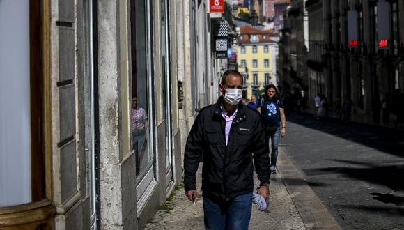 A man wearing a face mask walks at Chiado in Lisbon on March 14, 2020. - Portugal has so far reported 169 confirmed cases of coronavirus, far below neighboring Spain, where there are over 5,700 cases and dozens of fatalities. The governmnet has ordered schools to close next week due to the outbreak of the deadly virus, ordered nightclubs to close and imposed restrictions on the number of people who can visit restuarants. It has also announced that cruise ships would not be allowed to disembark passengers except those living in Portugal. (Photo by PATRICIA DE MELO MOREIRA / AFP)