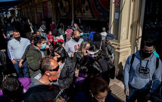 La gente se reúne afuera de una tienda luego de la flexibilización de las restricciones de cierre en medio de la pandemia en Santiago. (AFP/Martin Bernetti).