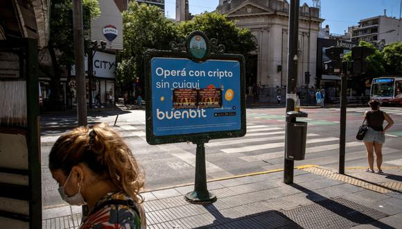 Los peatones esperan para cruzar en la Avenida Cabildo frente a un anuncio del intercambio de criptomonedas Buenbit en Buenos Aires, Argentina, el jueves 3 de marzo de 2022.