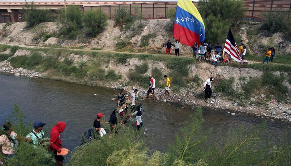 Migrantes venezolanos cruzan el río Bravo (o río Grande, como se le llama en EE. UU.) para realizar una manifestación contra las políticas migratorias de EE. UU. en Ciudad Juárez, México, el 31 de octubre de 2022. (Foto de HERIKA MARTINEZ / AFP)
