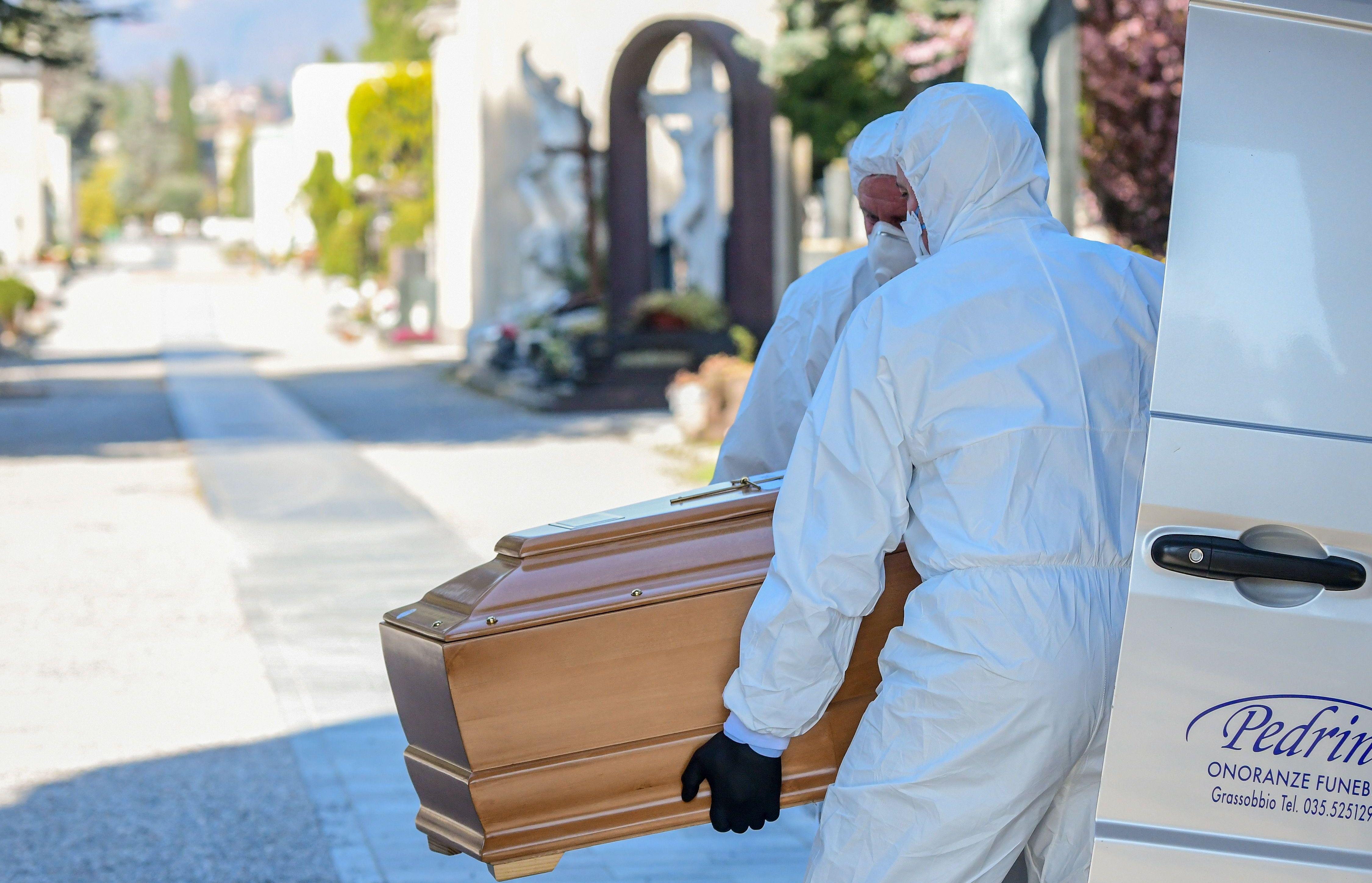 Trabajadores que usan una máscara para protegerse del coronavirus descargan un ataúd en el cementerio monumental de Bérgamo, Lombardía, mientras los entierros de las personas que murieron por Covid-19 se llevan a cabo a ritmo de uno cada media hora. (AFP / Piero Cruciatti).