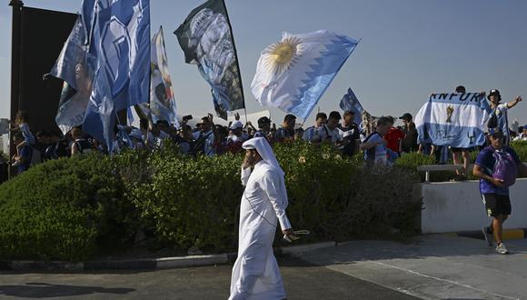 Un residente camina mientras los fanáticos argentinos se reúnen en el evento "Banderazo" apoyando a su equipo,  el 21 de noviembre de 2022, durante el torneo de fútbol de la Copa Mundial Qatar 2022. (Foto de PABLO PORCIUNCULA / AFP)