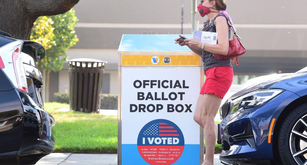 Una mujer que sostiene su boleta pasa junto a un buzón de votación por correo para las elecciones en Estados Unidos de 2020 en Monterey Park, California. (AFP / Frederic J. BROWN).
