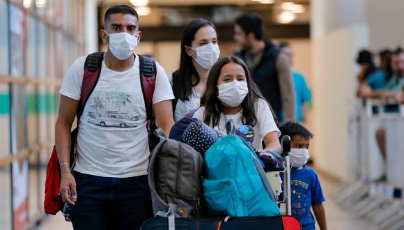Un grupo de pasajeros camina con máscaras protectoras como medida preventiva contra el coronavirus en el Aeropuerto Internacional Arturo Merino Benítez, en Santiago de Chile. (Foto: AFP)