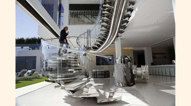El desarrollador Bruce Makowsky sube una escalera de acero artesanal junto a una gran escultura de una cámara Leica, en el interior de la mansión.