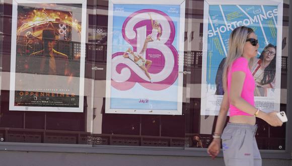 Una mujer pasa junto a carteles de las películas “Oppenheimer”, desde la izquierda, y “Barbie”.(Foto: Associated Press)