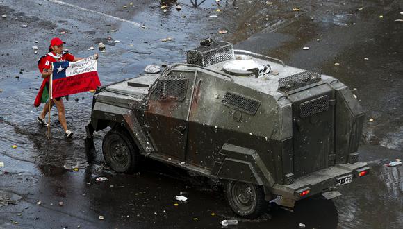 Una manifestante se acerca a un carro de la policía de Chile durante una protesta en Santiago. (AP Photo/Esteban Felix).