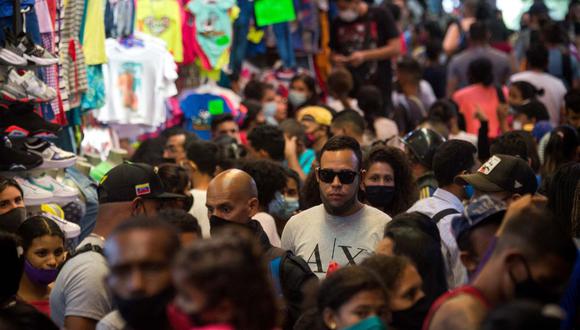 Un hombre con una mascarilla inapropiada camina entre una multitud en el mercado de La Hoyada en Caracas (Venezuela), el 17 de diciembre de 2020, en medio de la pandemia de coronavirus.  (Cristian Hernandez / AFP).