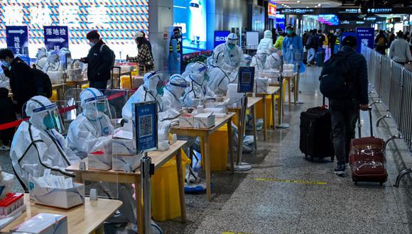 Trabajadores de la salud esperan para hacer pruebas de coronavirus covid-19 a los pasajeros después de su llegada a la estación de tren de Hongqiao en Shanghái, China, el 6 de diciembre de 2022. (HECTOR RETAMAL / AFP).