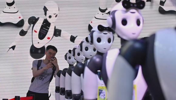 Un hombre toma una foto de robots durante la Conferencia Mundial de Inteligencia Artificial (WAIC) en Shanghái el 7 de julio de 2023. (Foto de WANG Zhao / AFP)