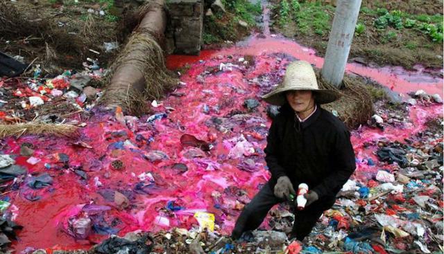 Una mujer intenta reciclar botellas en un contaminado lago, que ha sido teñido por diversos químicos tóxicos, de color fucsia fosforescente. (Foto: Lu Palmerini)