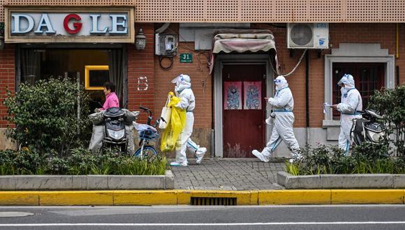 Trabajadores de la salud con equipo de protección como medida contra el coronavirus Covid-19 caminan por una calle en el distrito de Jing'an, en Shanghái, el 26 de marzo de 2022. (Héctor RETAMAL / AFP).